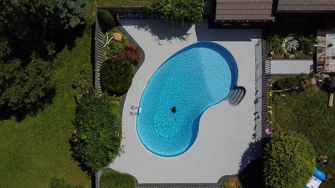 Grey rubber surfacing pool deck in a backyard