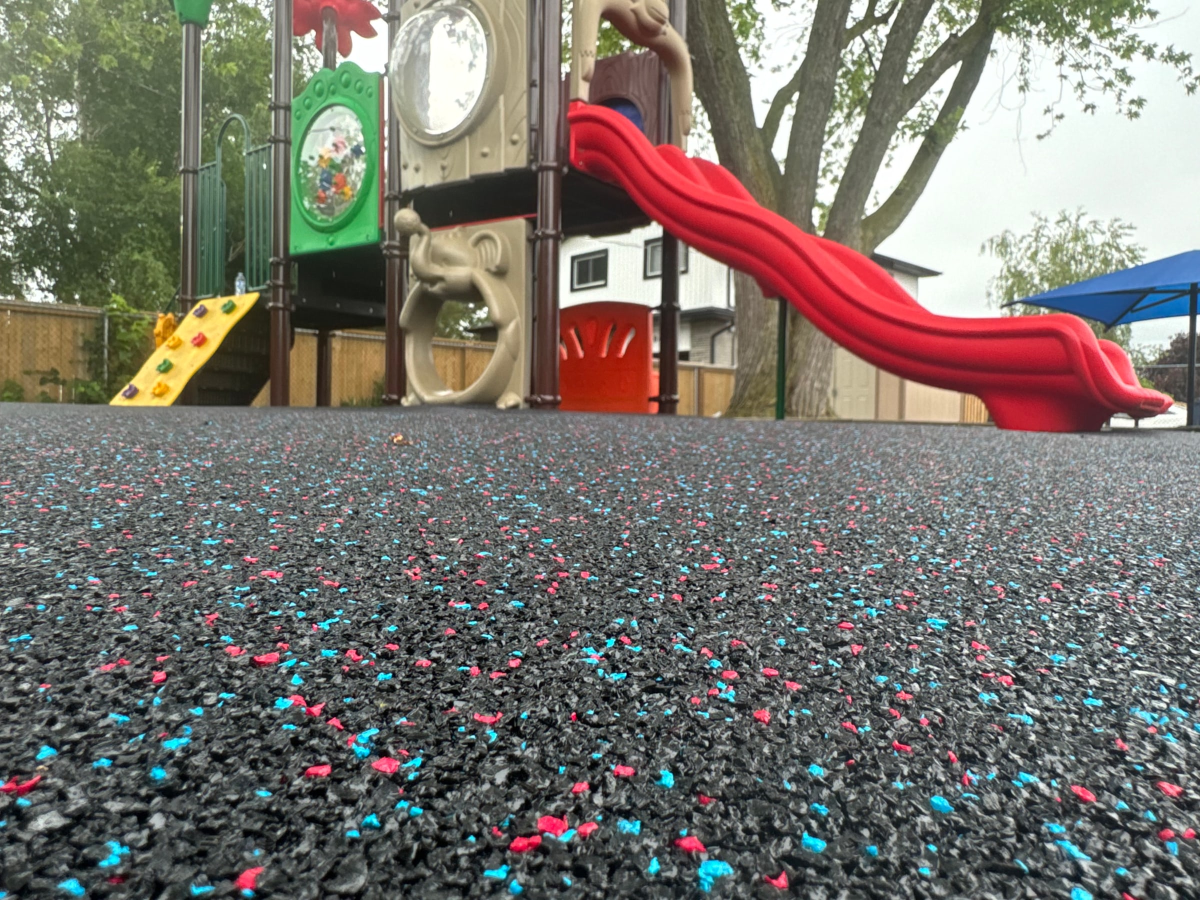 Red and blue rubber surfacing under a play slide