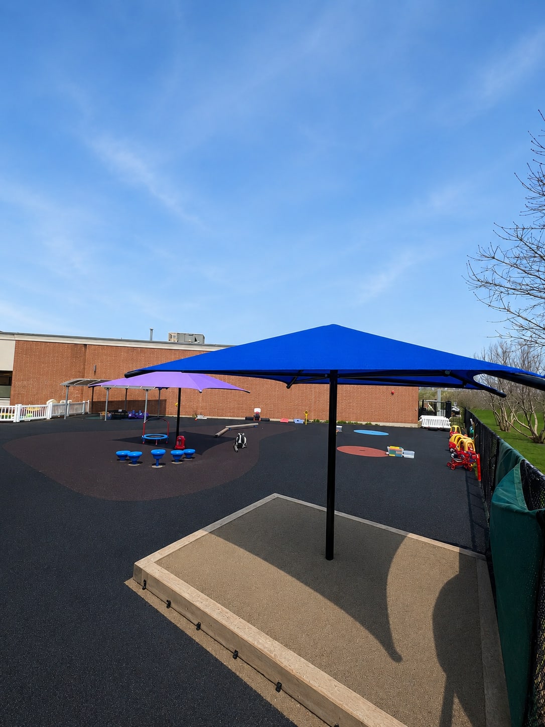 Blue and purple sun shade over a daycare sandbox