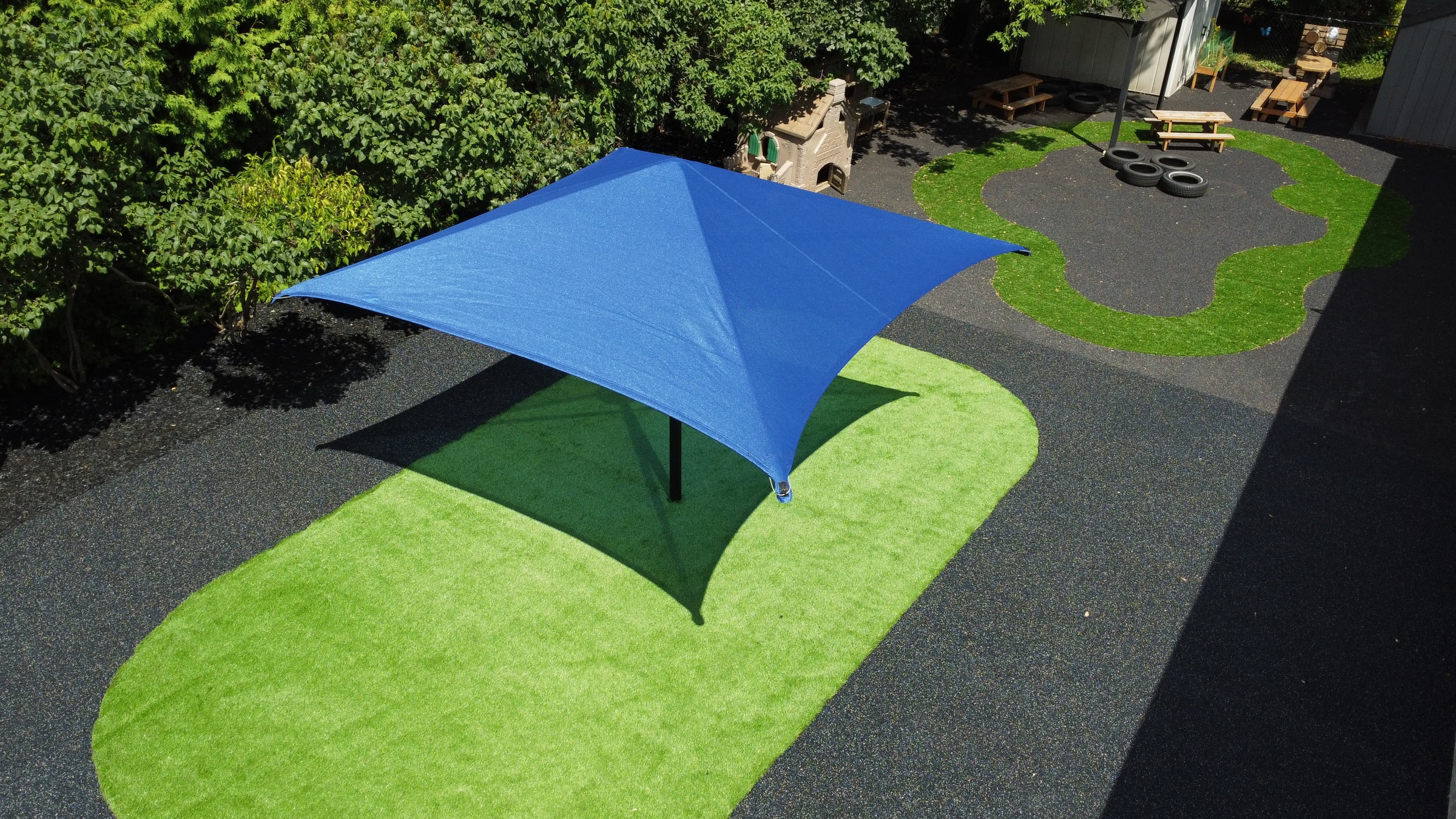 Blue shade structure with green turf at a daycare